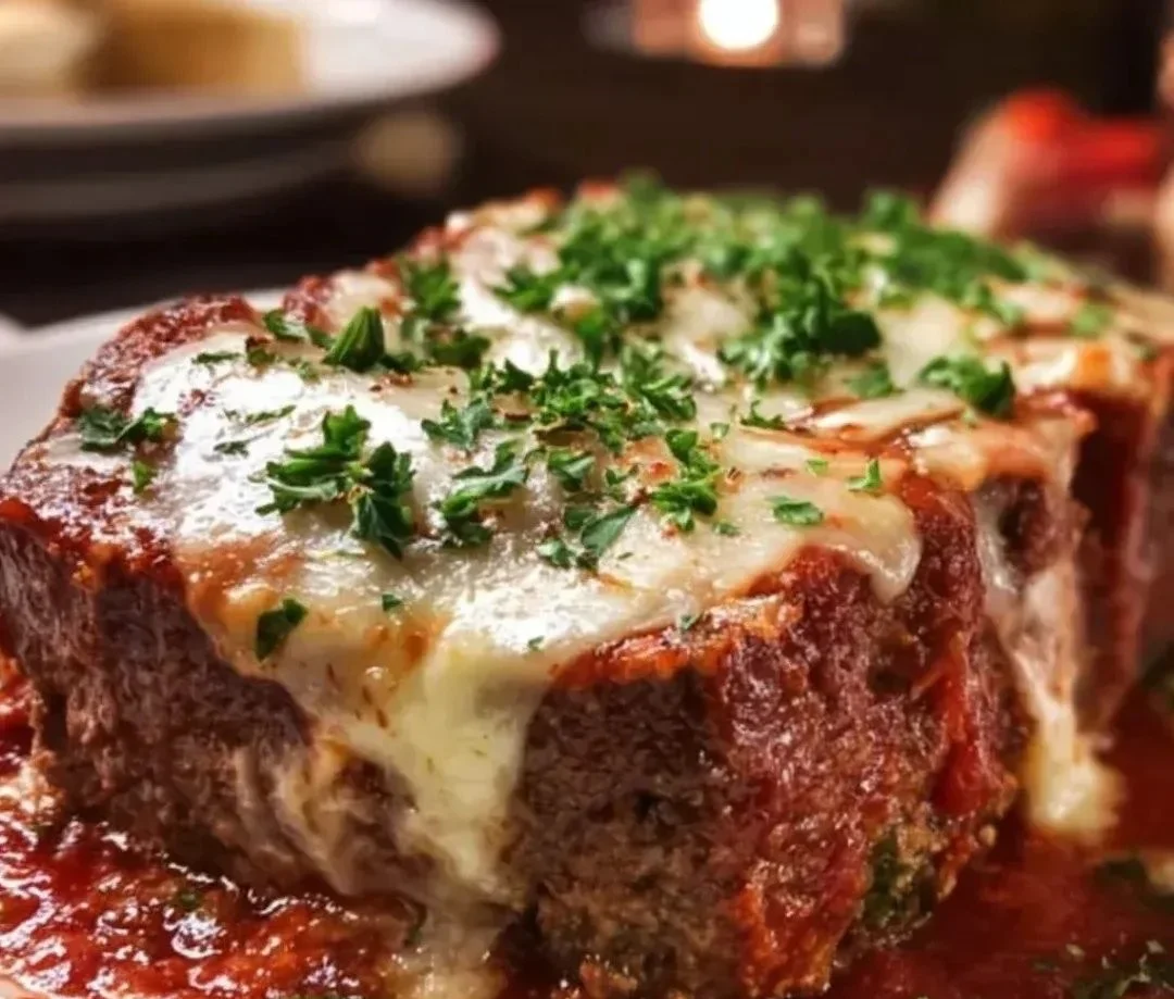 Mozzarella-stuffed Italian meatloaf served on a plate with herbs and sauce.