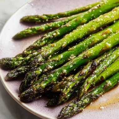 Roasted baked asparagus drizzled with olive oil on a serving plate