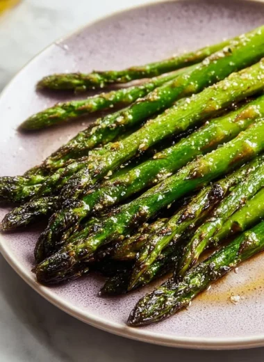 Roasted baked asparagus drizzled with olive oil on a serving plate