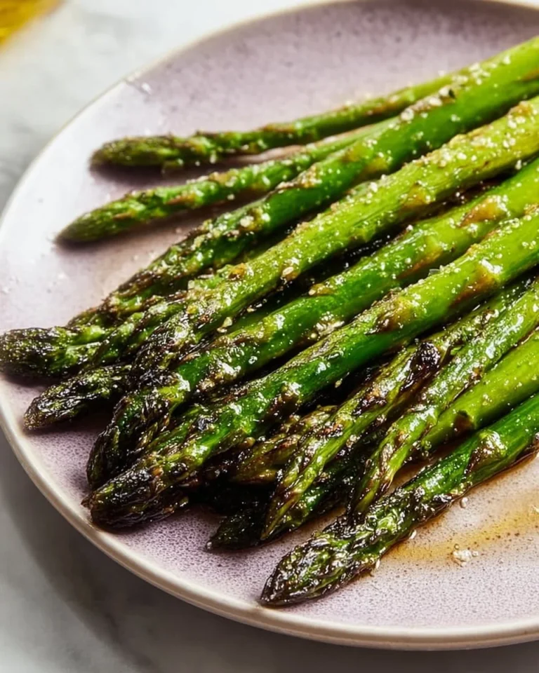 Roasted baked asparagus drizzled with olive oil on a serving plate
