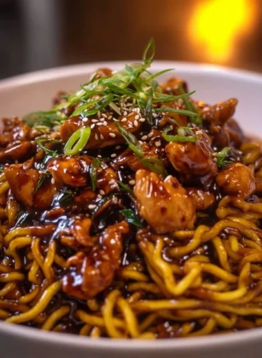 Sticky garlic chicken noodles garnished with herbs and served in a bowl.