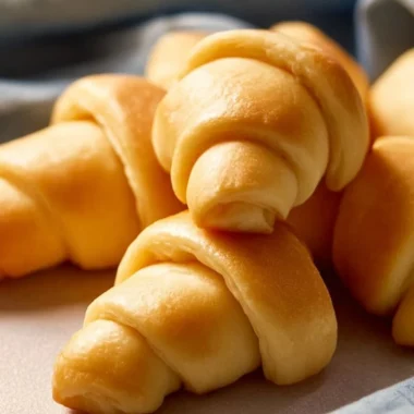 Freshly baked crescent rolls, golden and flaky, served on a plate.