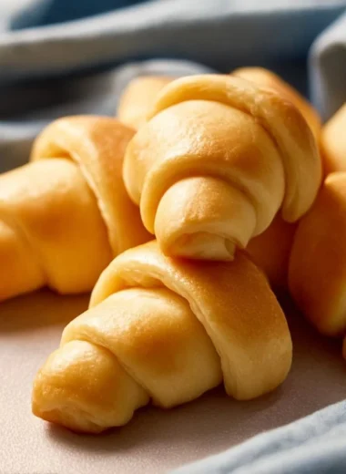 Freshly baked crescent rolls, golden and flaky, served on a plate.