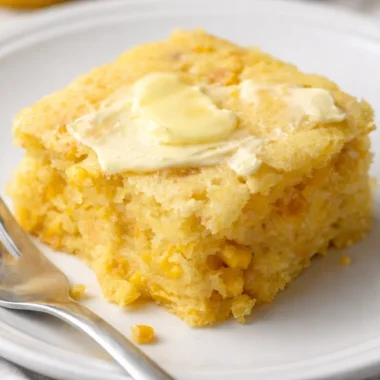 Delicious cornbread casserole topped with melted cheese and served in a baking dish.