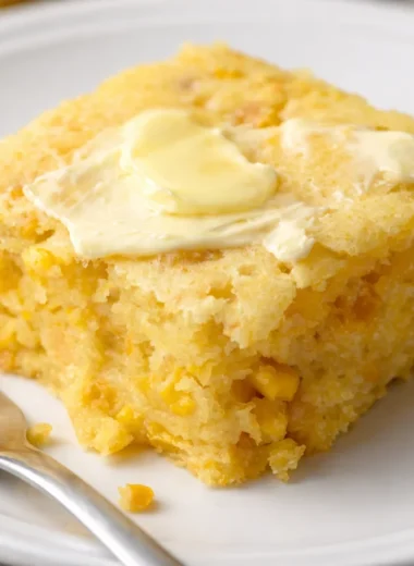 Delicious cornbread casserole topped with melted cheese and served in a baking dish.