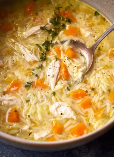 Bowl of easy lemon chicken orzo soup garnished with fresh herbs