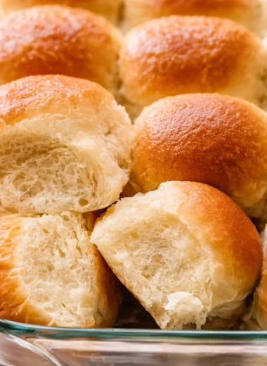 Freshly baked homemade dinner rolls on a rustic wooden table.