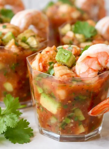 Chilled shrimp cocktail with horseradish sauce garnished with lemon and herbs.