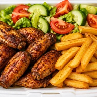 Crispy chicken wings with thick-cut fries and garden salad on a plate