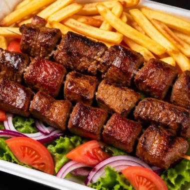 Grilled steak skewers served with crispy fries and a fresh salad.