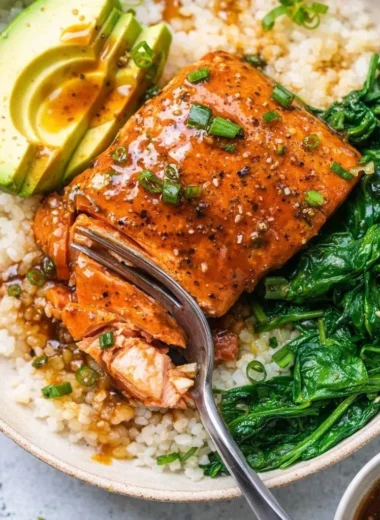 Teriyaki salmon rice bowl with vegetables and garnishes
