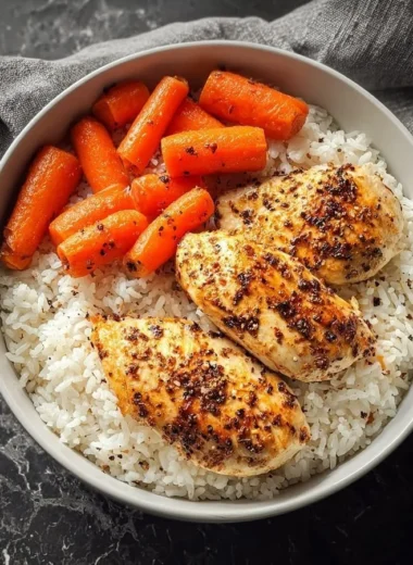 Plate of black pepper chicken breast with rice and glazed carrots