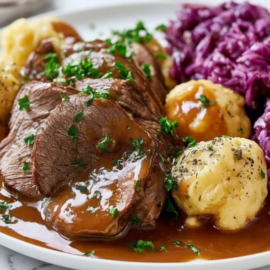 Traditional Sauerbraten served with sides like red cabbage and dumplings